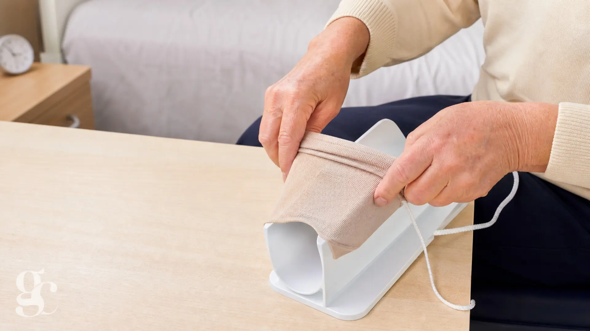 Une personne prépare une chaussette sur la gouttière d’un enfile-chaussettes